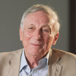 Professor David Hill AO. Man wearing brown jacket and blue shirt.